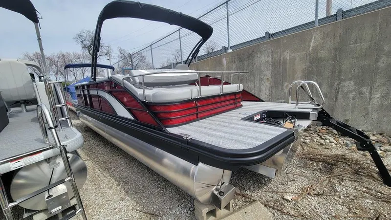 Slide: The Image of 2025 Bennington 24 SXSB pontoon boat with red accents, docked outdoors. - 9