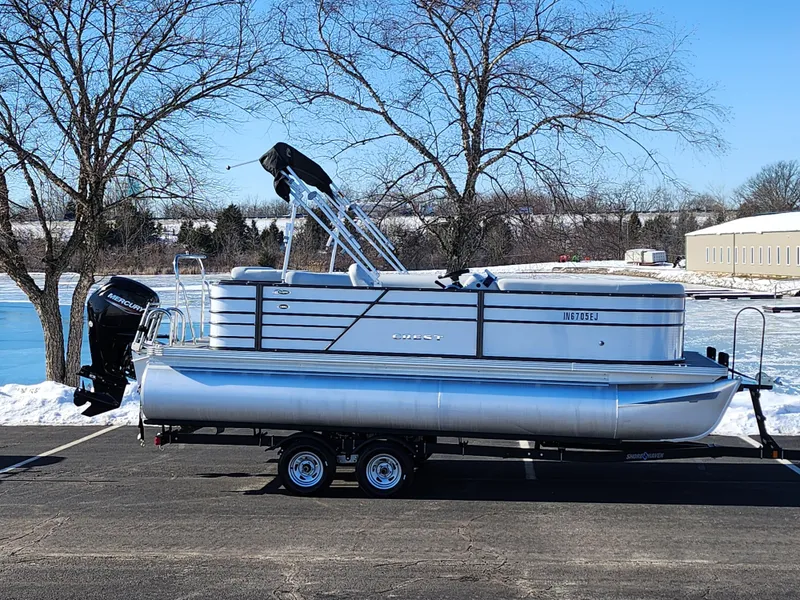 Slide: The Image of 2022 Crest Classic LX 200 pontoon boat on trailer, parked near snowy lake. - 0