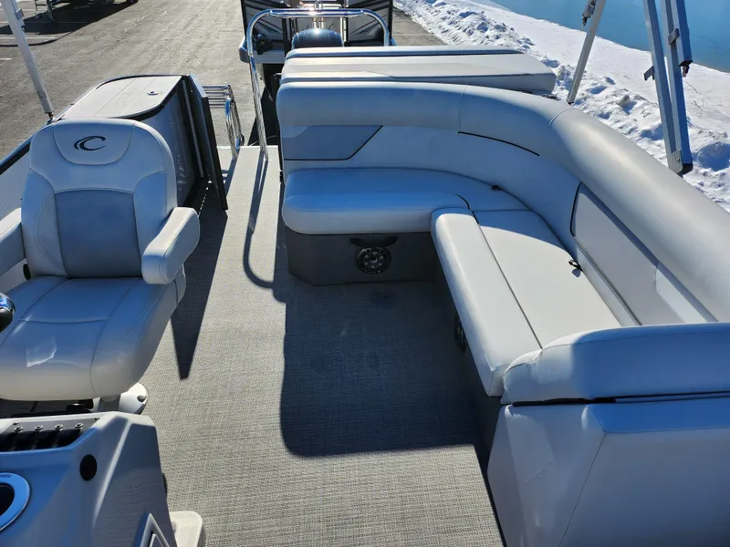 Slide: The Image of 2022 Crest Classic LX 200 pontoon boat interior with plush seating and steering console. - 14