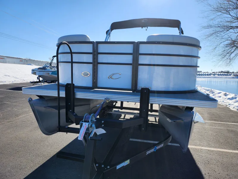 Slide: The Image of 2022 Crest Classic LX 200 pontoon boat on trailer, parked near snowy waterfront. - 6