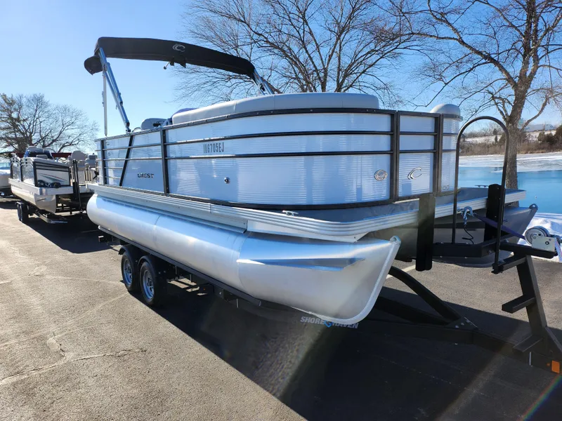 Slide: The Image of 2022 Crest Classic LX 200 pontoon boat on trailer, parked near a lake. - 8