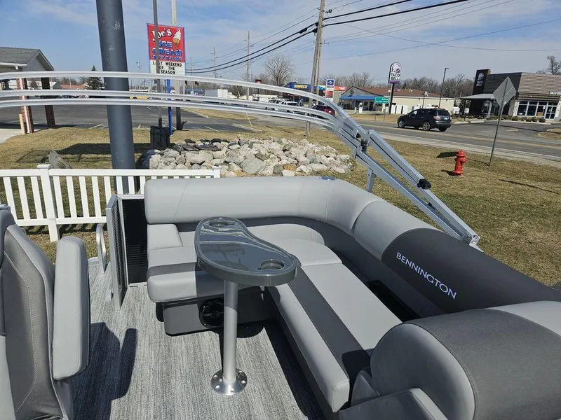 Slide: The Image of 2025 Bennington 188 SL pontoon boat with gray seating and table, parked near a road. - 5