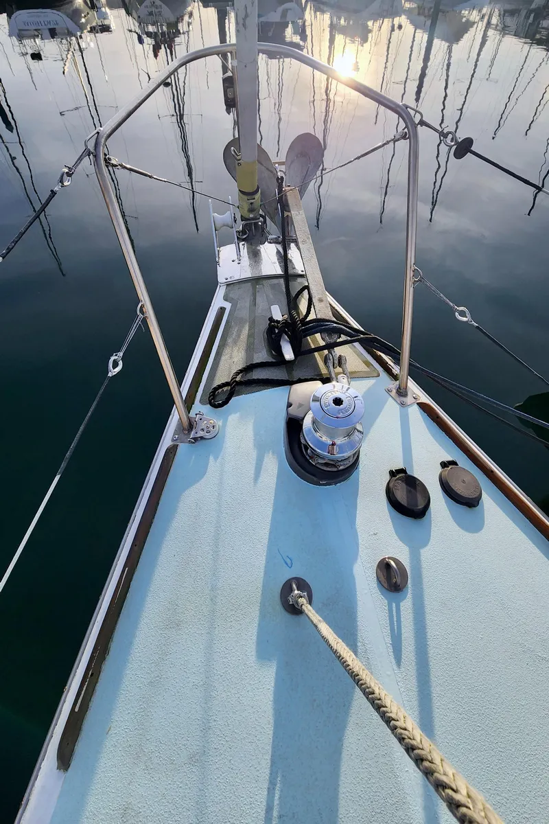 Slide: The Image of 1985 Farr 50 sailboat deck with winch, ropes, and calm marina reflection. - 11