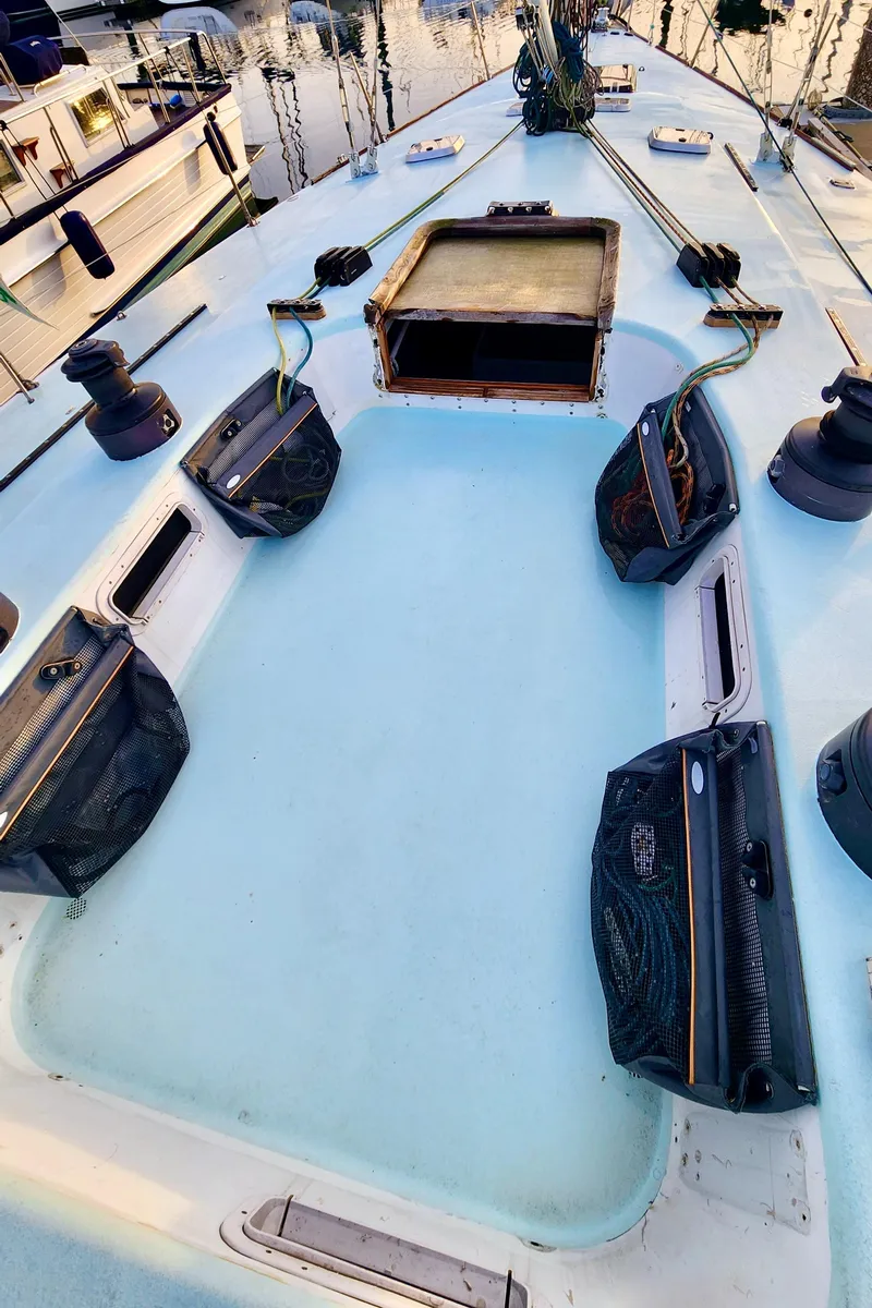 Slide: The Image of 1985 Farr 50 sailboat deck with hatches and winches, docked at marina. - 14