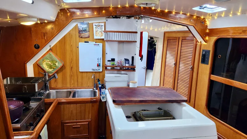 Slide: The Image of Cozy 1985 Farr 50 yacht interior with wooden cabinetry, kitchen area, and ambient lighting. - 15