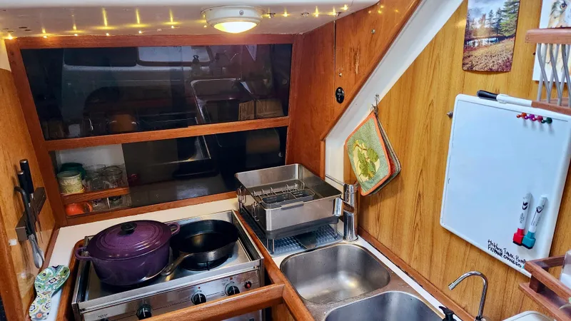 Slide: The Image of Compact kitchen in a 1985 Farr 50 yacht with stove, sink, and wooden cabinetry. - 16