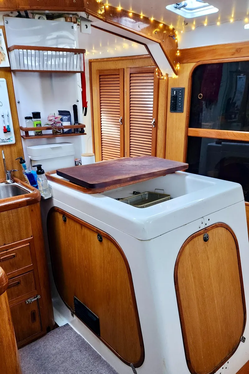 Slide: The Image of 1985 Farr 50 yacht interior with wooden cabinetry, sink, and cozy lighting. - 19