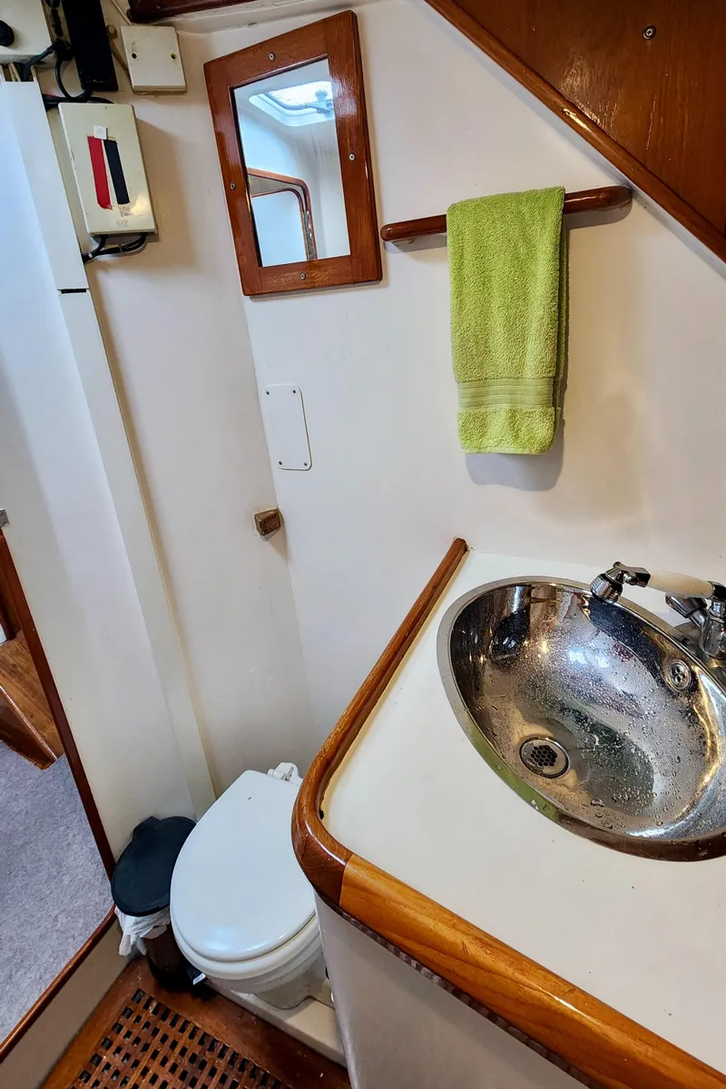 Slide: The Image of 1985 Farr 50 yacht bathroom with sink, toilet, mirror, and green towel. - 23