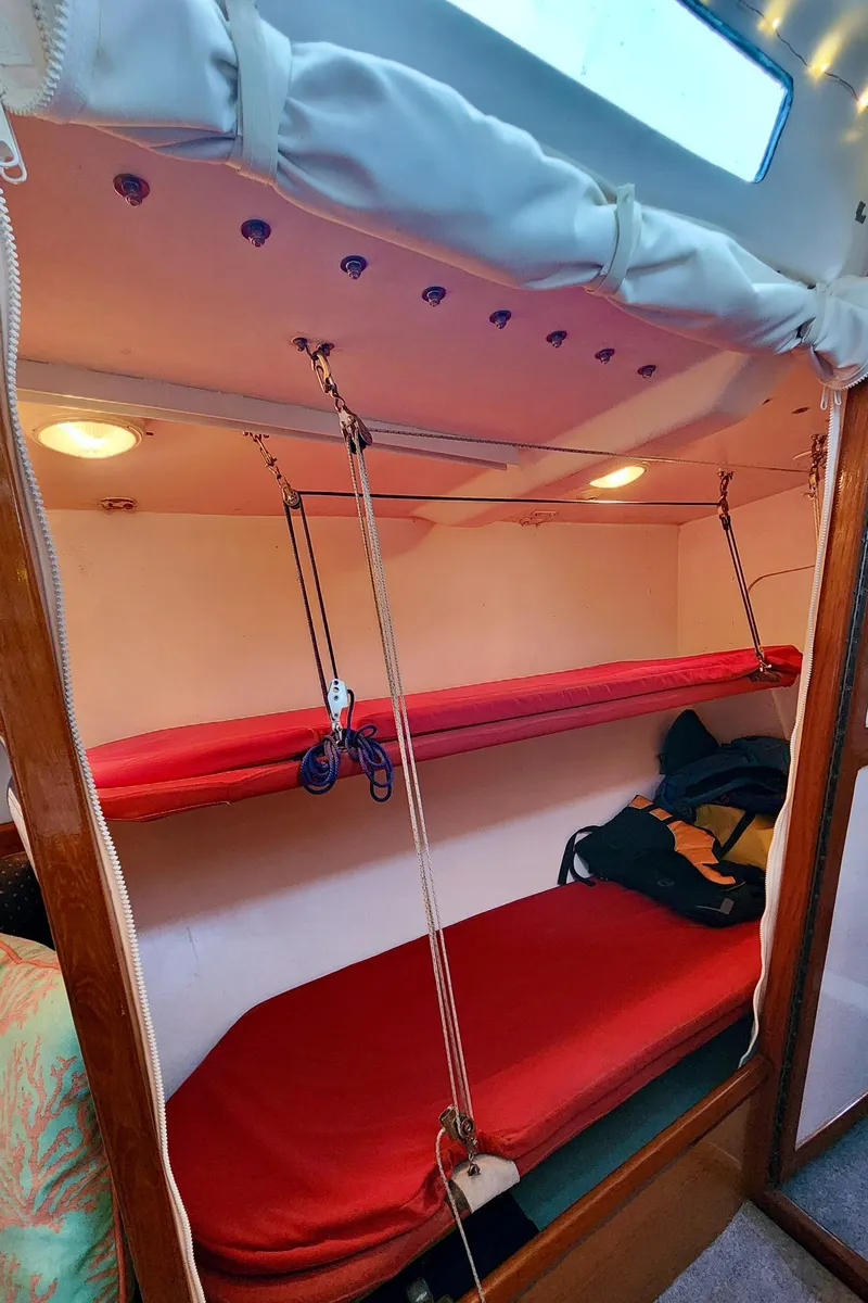 Slide: The Image of Interior of 1985 Farr 50 yacht with red bunk beds and cozy lighting. - 29