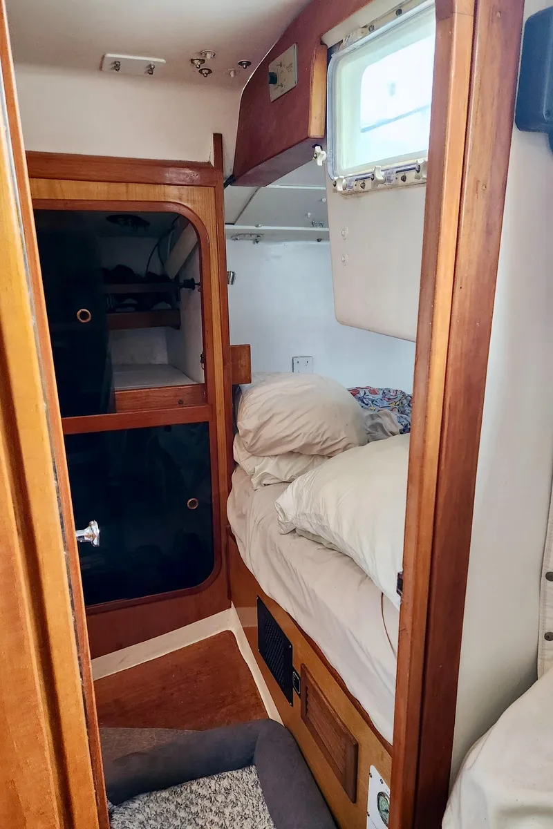 Slide: The Image of Cozy cabin interior of a 1985 Farr 50 sailboat with wooden furnishings and bedding. - 37