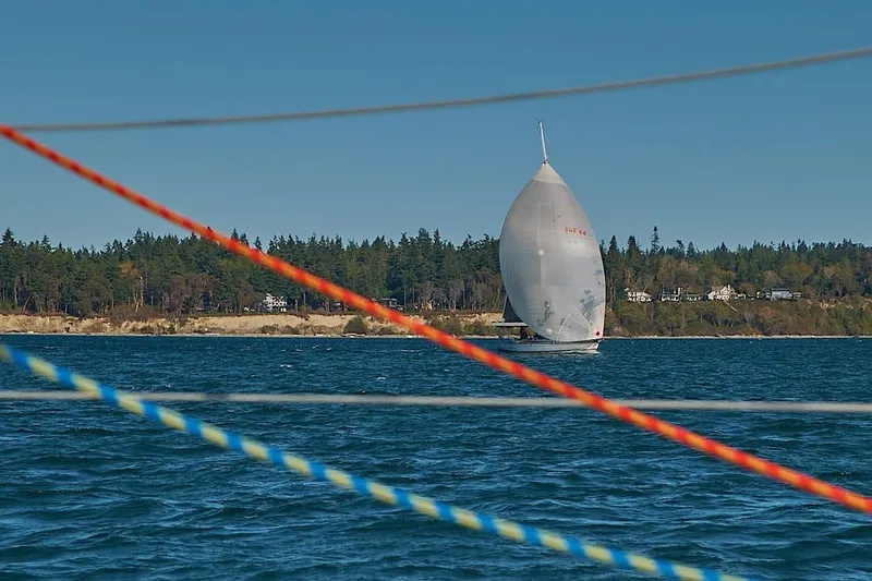 Slide: The Image of Sailboat with spinnaker on water, Farr 50 model, 1985, forested shoreline in background. - 43