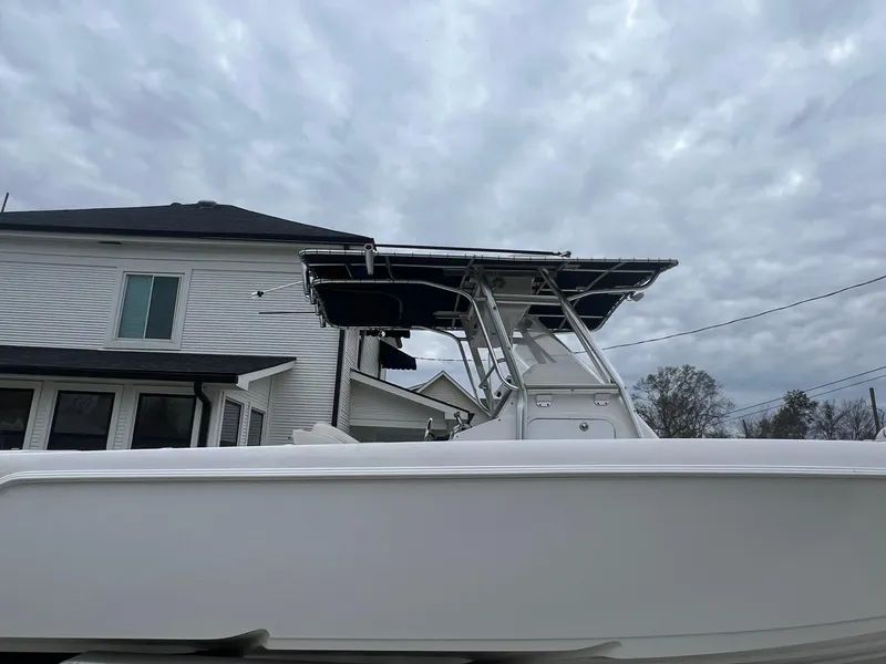 Slide: The Image of 2001 Donzi 32 ZF Open boat with T-top, parked near a house under cloudy skies. - 22
