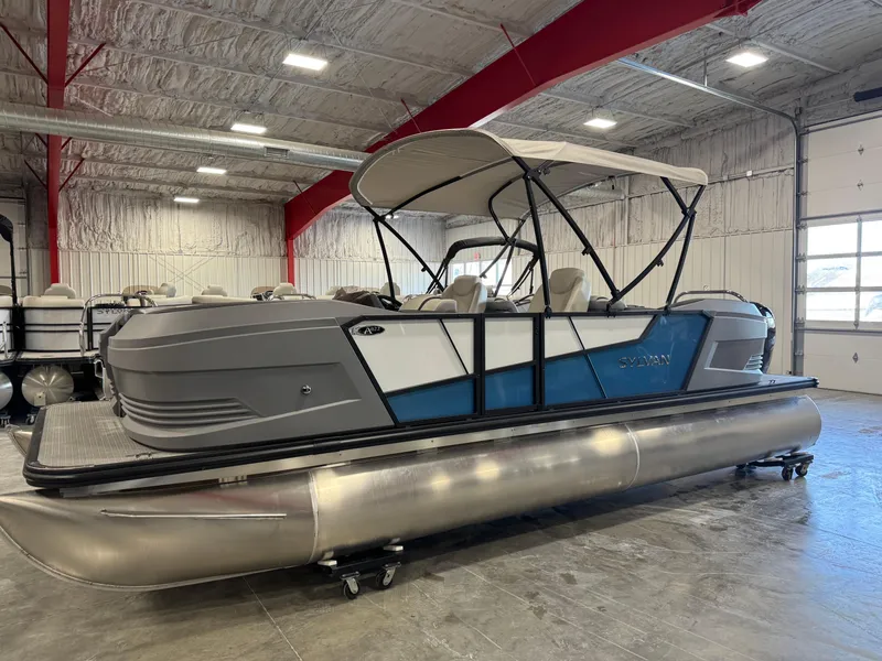 The Image of 2025 Sylvan A-22 Sport pontoon boat in showroom, featuring sleek design and canopy. - 1