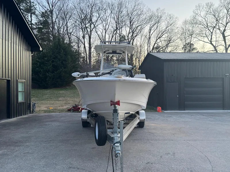 Slide: The Image of 2023 Boston Whaler 250 Dauntless boat on trailer, parked near black buildings. - 2