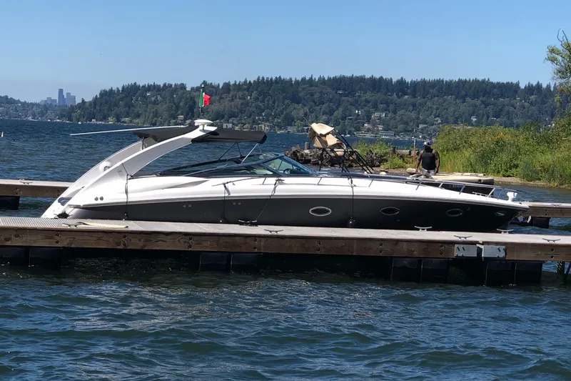 The Image of 2005 Cobalt 360 boat docked on a scenic lake with forested hills in the background. - 0