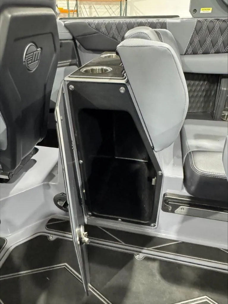 Slide: The Image of 2024 Malibu M242 boat interior with open storage compartment and cup holders. - 11