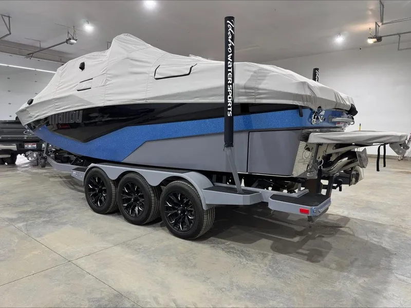 Slide: The Image of 2024 Malibu M242 boat covered, on a trailer, in a garage setting. - 4
