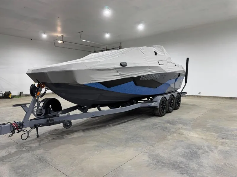 Slide: The Image of 2024 Malibu M242 boat covered on a trailer in a spacious indoor setting. - 8