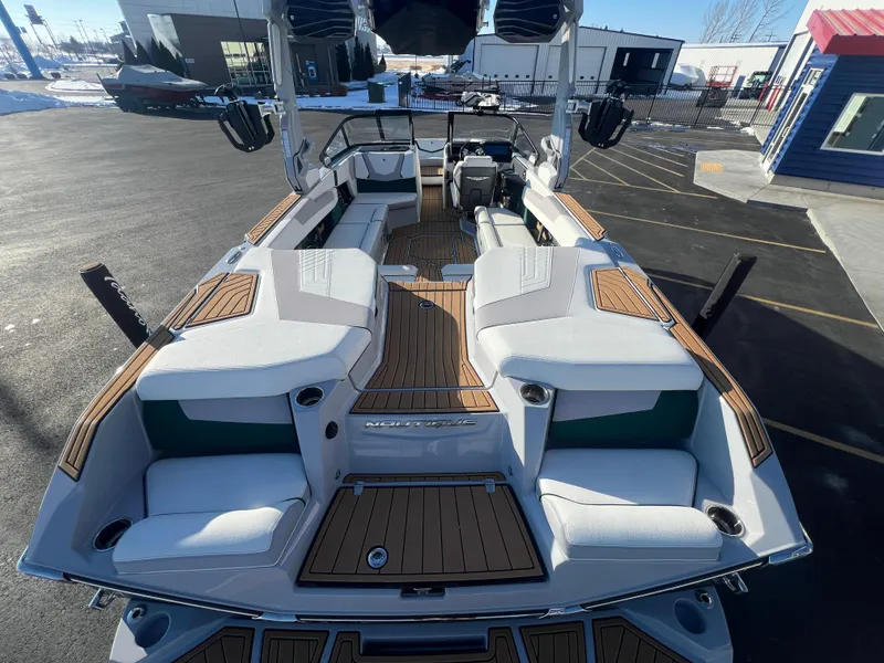 Slide: The Image of 2024 Nautique G25 boat with spacious seating and sleek design, parked outdoors. - 12