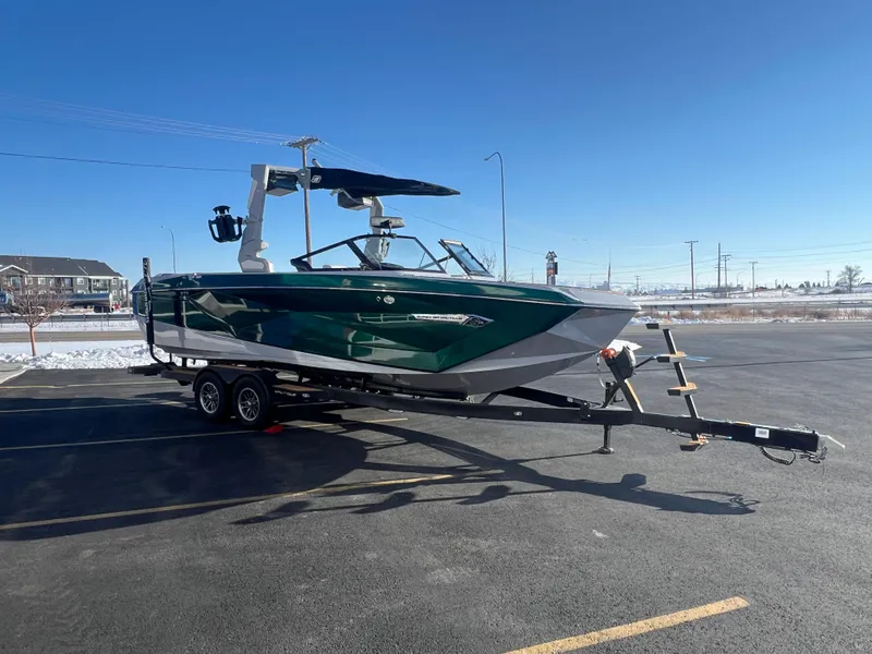 Slide: The Image of 2024 Nautique G25 boat on trailer in parking lot under clear blue sky. - 8