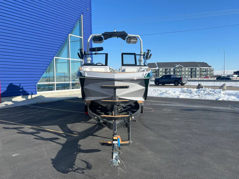 Slide: The Image of 2024 Nautique G25 boat on trailer, parked outside a blue building in a snowy setting. - 9