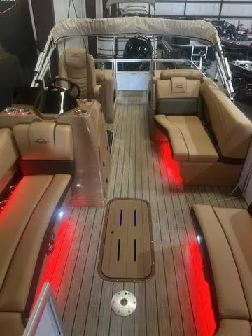 Slide: The Image of 2025 SunCatcher Fusion Series 324SS boat interior with red LED lighting and tan seating. - 7