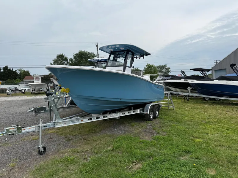 The Image of 2025 Sportsman Open 212 Center Console boat on trailer, parked on grass. - 1