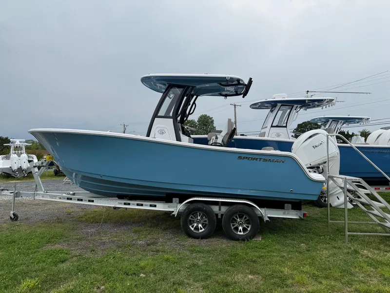 Slide: The Image of 2025 Sportsman Open 212 Center Console boat on trailer, blue hull, parked on grass. - 4