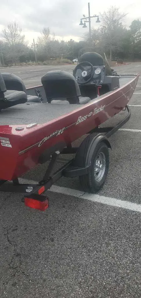 Slide: The Image of 2025 Tracker Bass Tracker Classic XL boat in a parking lot, red exterior, side view. - 2
