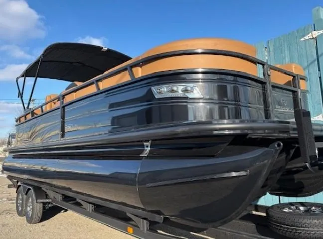 Slide: The Image of 2024 Regency 250 LE3 pontoon boat on trailer, featuring sleek black design and tan accents. - 1