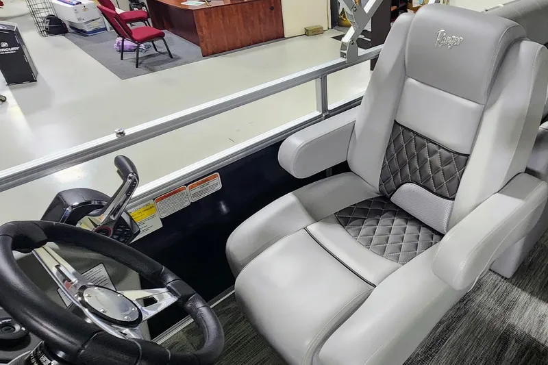 Slide: The Image of Captain's seat of 2025 Ranger Reata 243C boat with steering wheel and controls. - 11