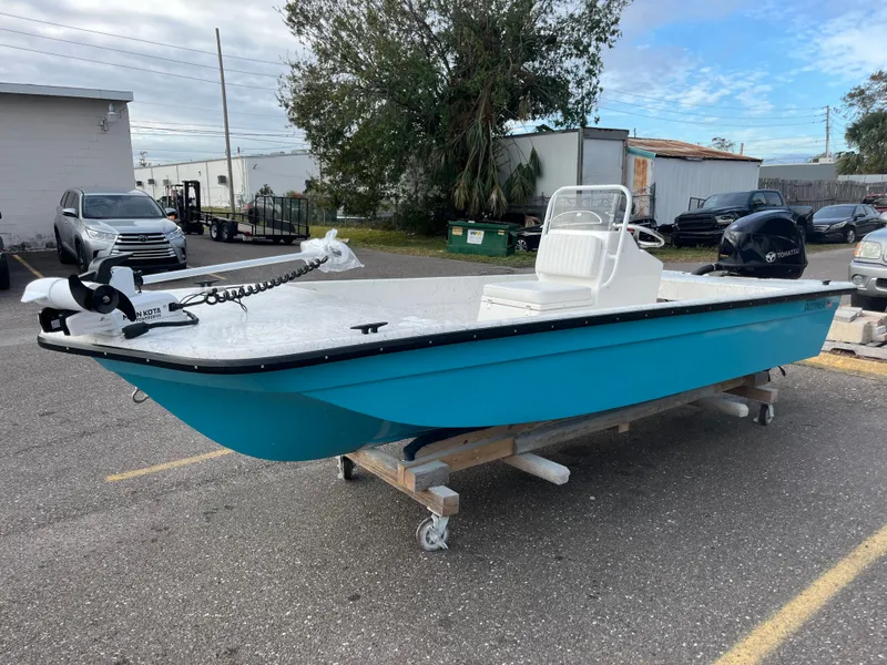 Slide: The Image of 2025 Rabco 16' Buccaneer boat in parking lot, blue hull, white deck, outboard motor. - 1