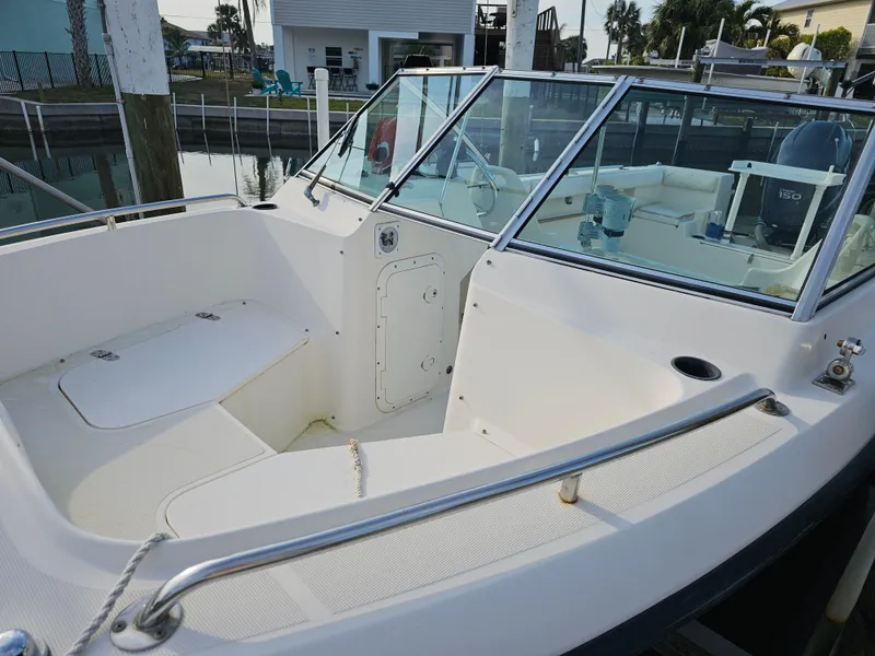 Slide: The Image of 1994 Pursuit 2150 DC boat interior with seating and windshield, docked near waterfront homes. - 5
