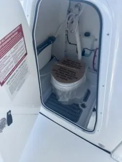 Slide: The Image of 2025 Tidewater 232 LXF boat interior with compact marine toilet setup. - 13