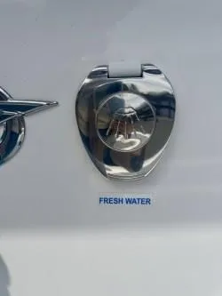 Slide: The Image of 2025 Tidewater 232 LXF boat fresh water inlet with chrome cover. - 6