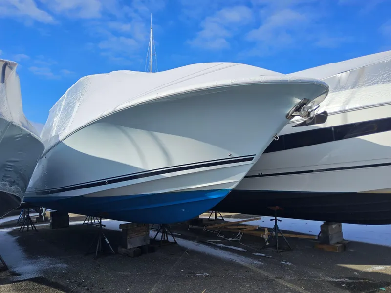 Slide: The Image of 2017 Southport 33 LX boat covered and elevated, with a blue hull, under a clear sky. - 3