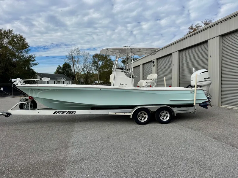Slide: The Image of 2020 BlackJack 256 Bay boat on trailer, parked near storage units. - 2