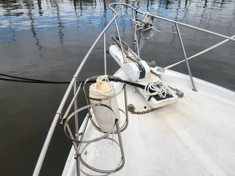 Slide: The Image of 1981 Mainship 34 Trawler bow with anchor and railing, docked on calm water. - 11