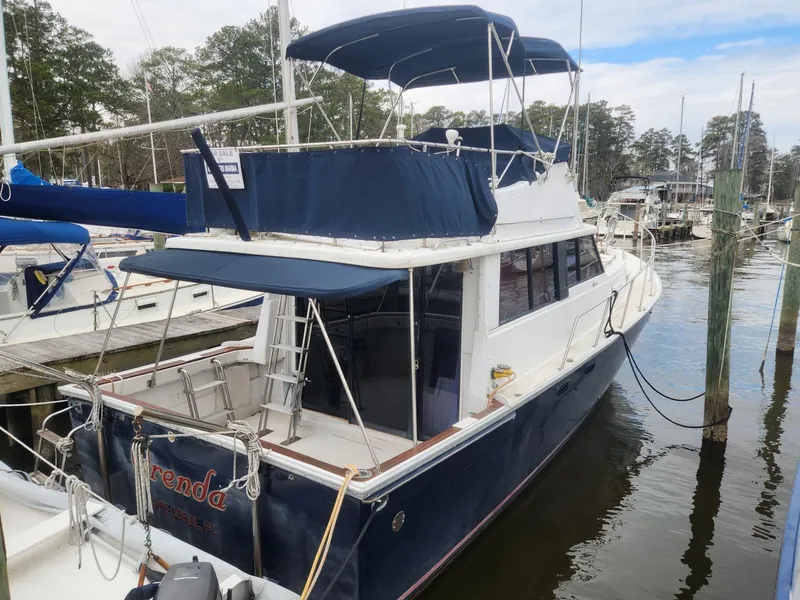 Slide: The Image of 1981 Mainship 34 Trawler docked at marina, featuring blue canopy and spacious deck. - 2