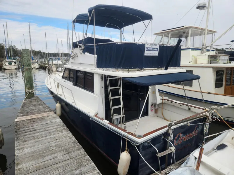 Slide: The Image of 1981 Mainship 34 Trawler docked at marina, featuring blue canopy and "For Sale" sign. - 3