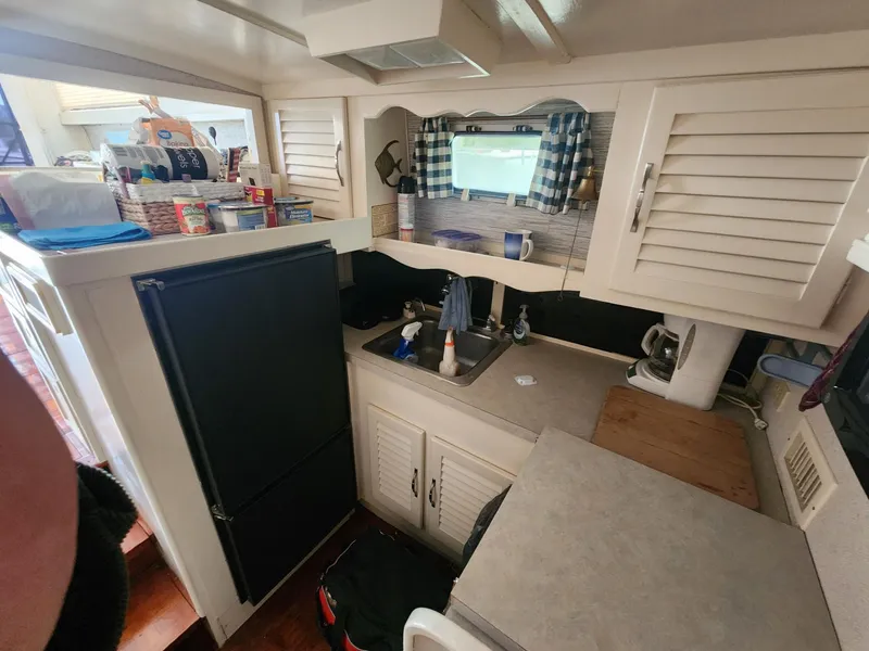 Slide: The Image of 1981 Mainship 34 Trawler kitchen with sink, fridge, and storage cabinets. - 32