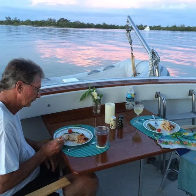 Slide: The Image of Man dining on 1981 Mainship 34 Trawler, enjoying a meal with a scenic water view. - 5