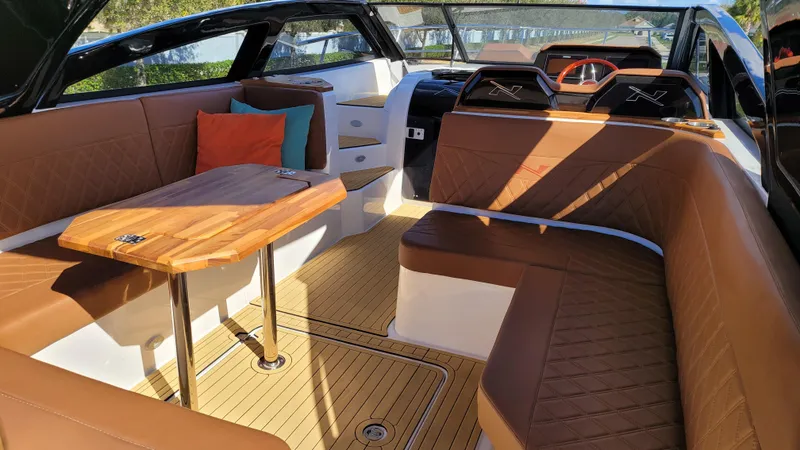 Slide: The Image of 2023 NX Boats NX340 interior with brown leather seating and wooden table. - 10