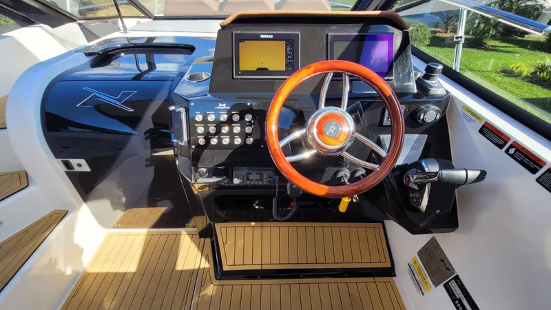 Slide: The Image of 2023 NX Boats NX340 helm with wooden steering wheel and modern controls. - 13