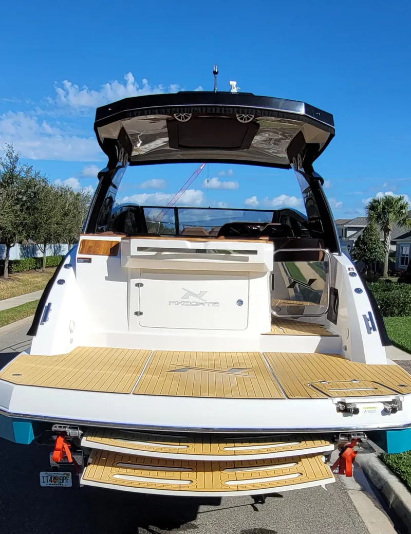 Slide: The Image of 2023 NX Boats NX340, rear view, docked, showcasing spacious deck and modern design. - 14