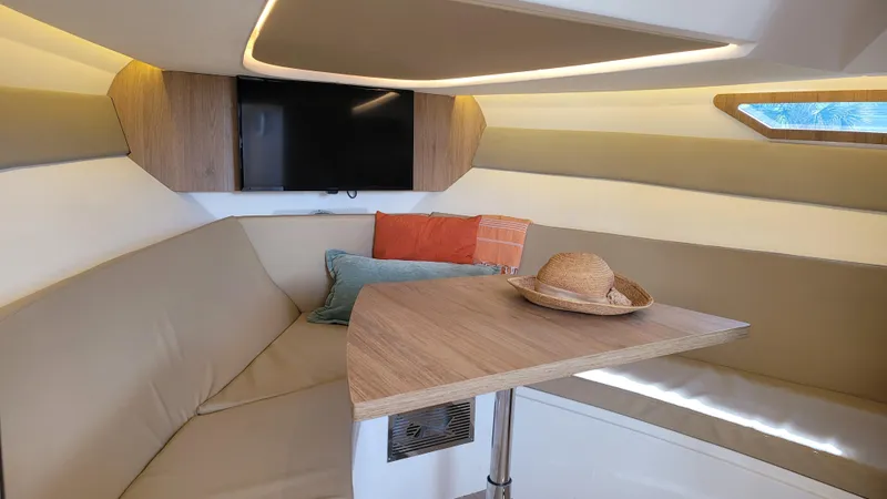 Slide: The Image of Interior of 2023 NX Boats NX340, featuring cozy seating, table, and modern decor. - 16
