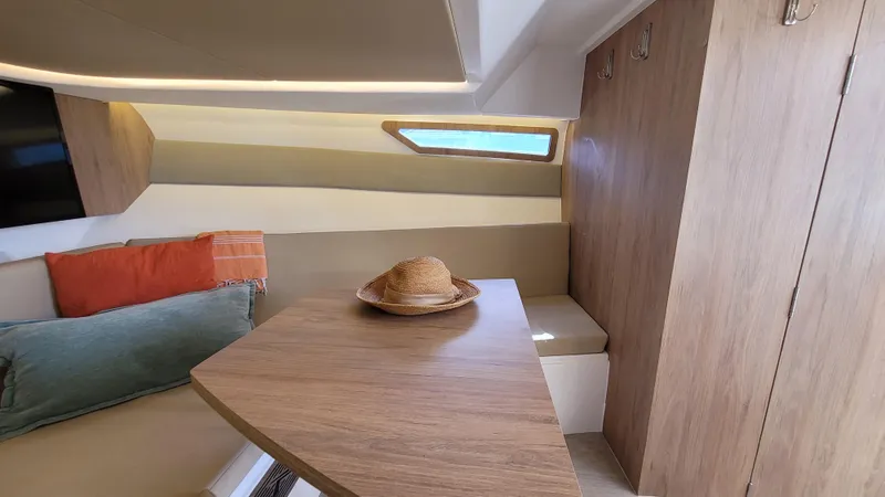 Slide: The Image of Interior of 2023 NX Boats NX340, featuring cozy seating and wooden table. - 17