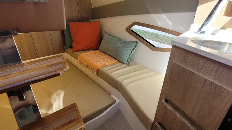 Slide: The Image of 2023 NX Boats NX340 interior with cozy seating, cushions, and wooden accents. - 19