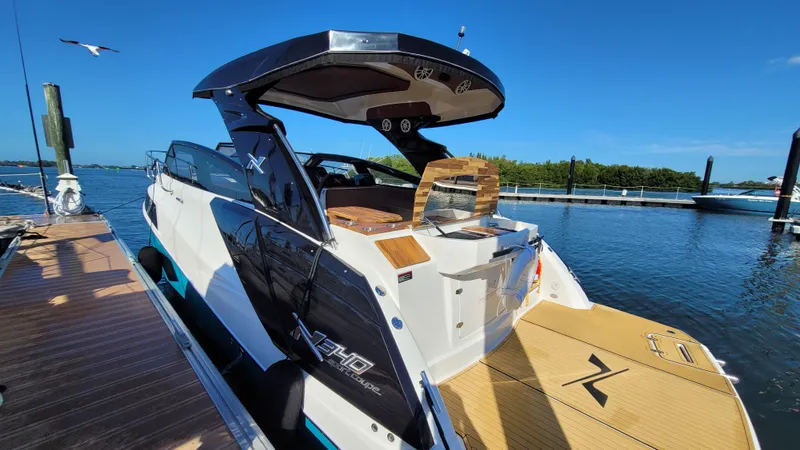 Slide: The Image of 2023 NX Boats NX340 docked, showcasing sleek design and luxurious features against a serene waterfront backdrop. - 2