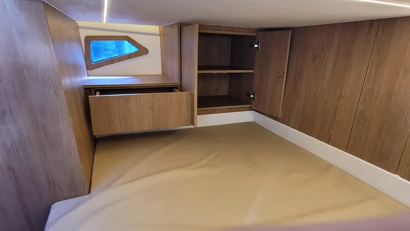 Slide: The Image of 2023 NX Boats NX340 cabin interior with wood finish, storage, and window. - 21